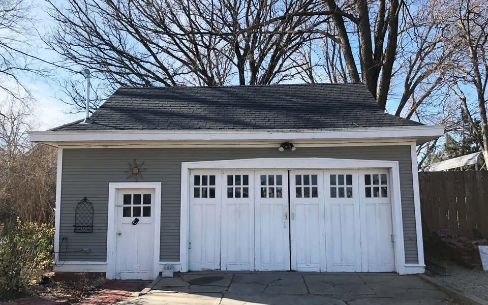 Historic carriage-house garage with paneled overhead doors and upper gable windows