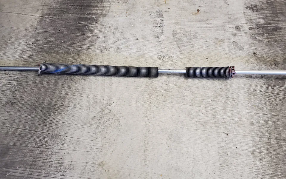 Overhead garage door torsion spring and shaft assembly mounted above a sectional door